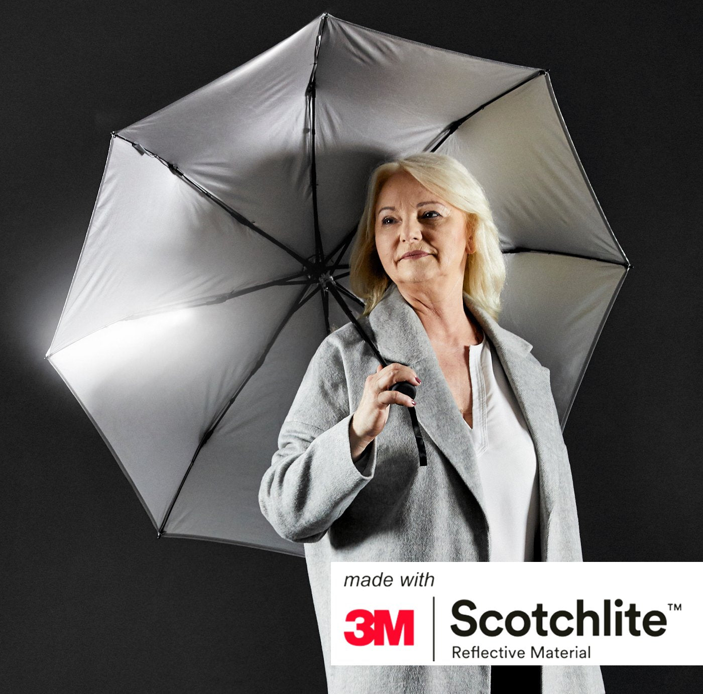 Person hält aufgeklappten Regenschirm mit sichtbarer silberfarbener Innenbeschichtung