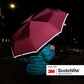Person von hinten hält aufgeklappten dunkelroten Regenschirm mit leuchtenden, reflektierenden Rändern bei Nacht